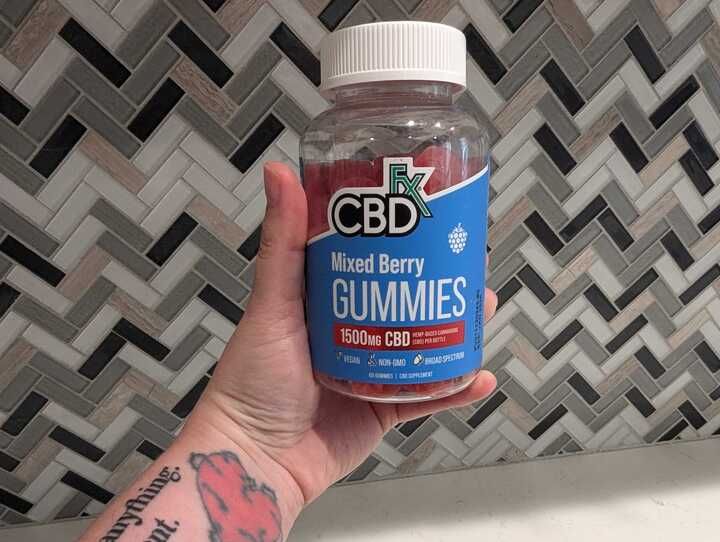 Healthline tester holding a bottle of CBDfx gummies