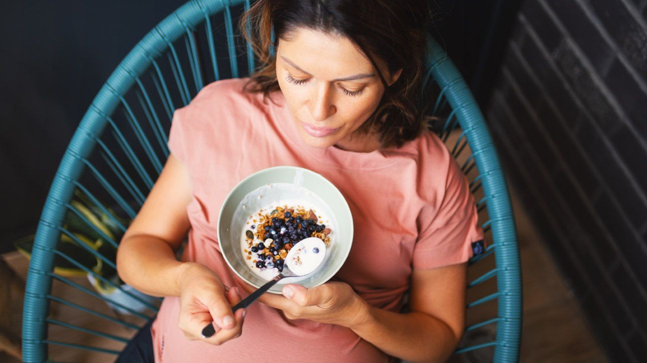 A pregnant woman eating yogurt.