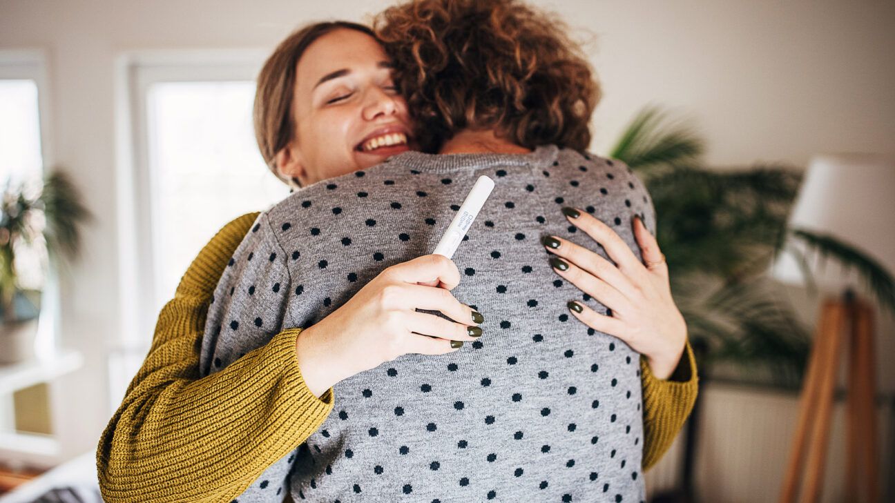 A female with a pregnancy test hugging a male.