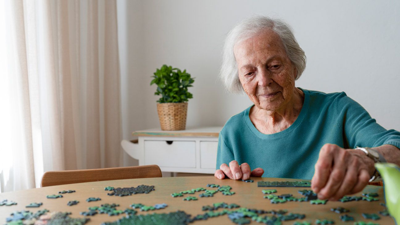 An older woman does a puzzle at home