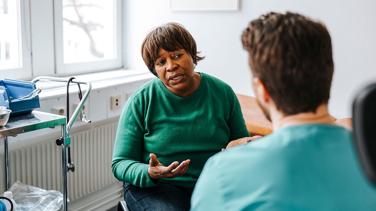 senior woman talking with healthcare professional in exam room