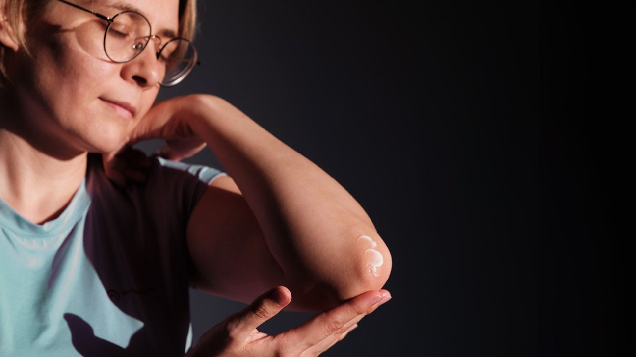 A woman moisturizes her elbow