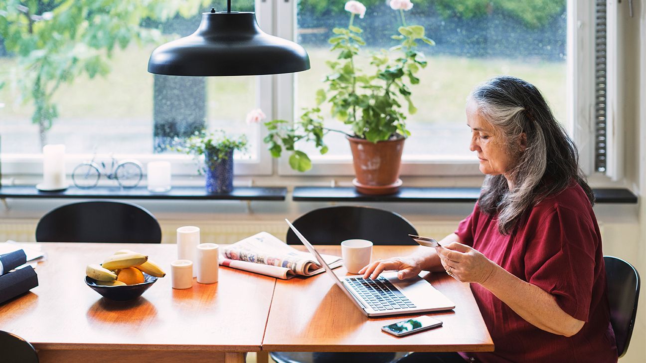 senior female at home using laptop computer in kitchen