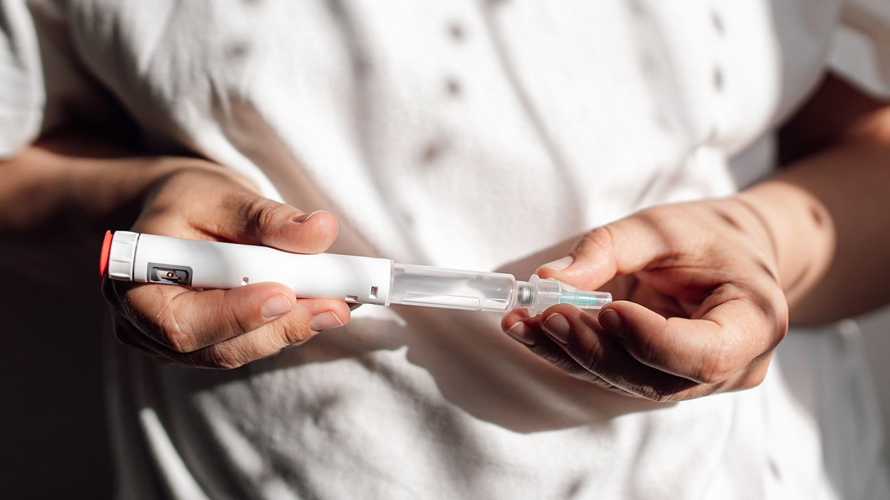 Close-up of light-skinned person holding an injection pen in both hands