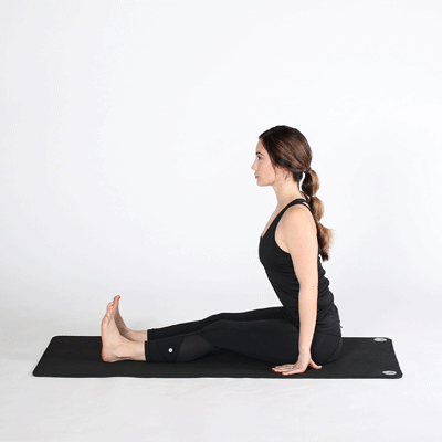 Woman doing seated forward fold on a yoga mat