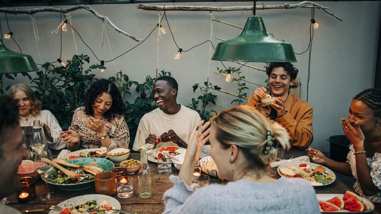 Multi race group of friends sitting around a dinner table