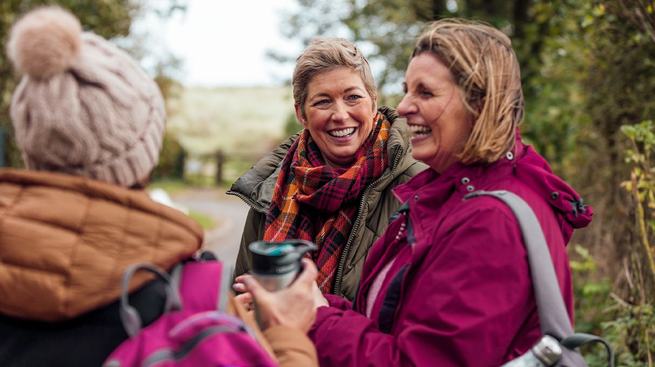 Three adult friends laughing in the countryside.