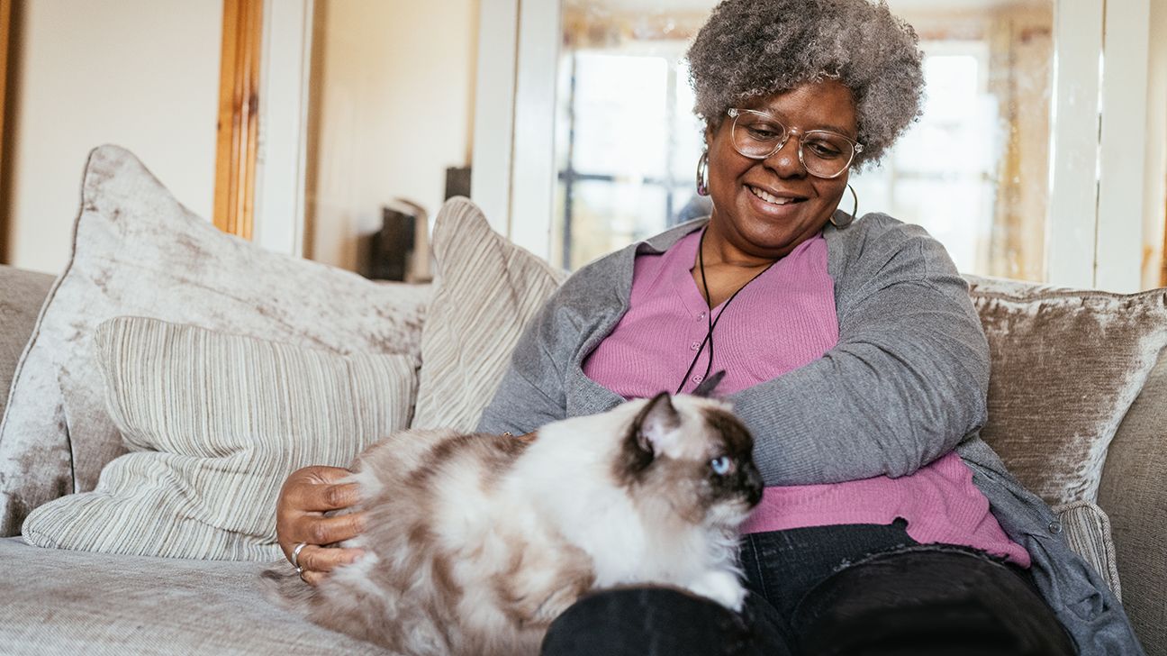 older adult sitting on sofa at home with pet cat