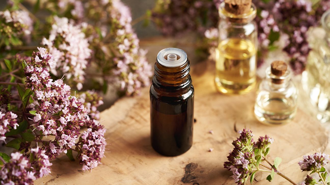 bottle of oregano oil next to oregano plants