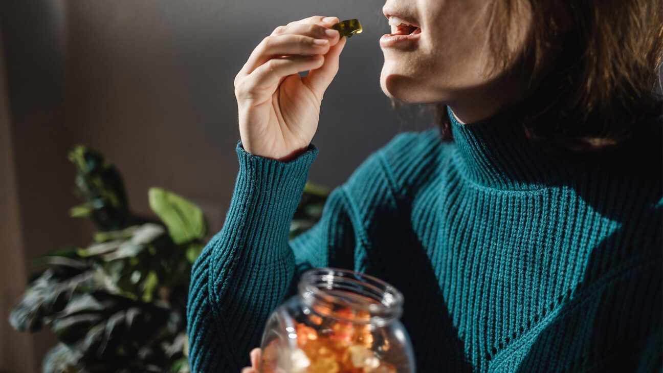 Female teal sweater eats cannabis gummies