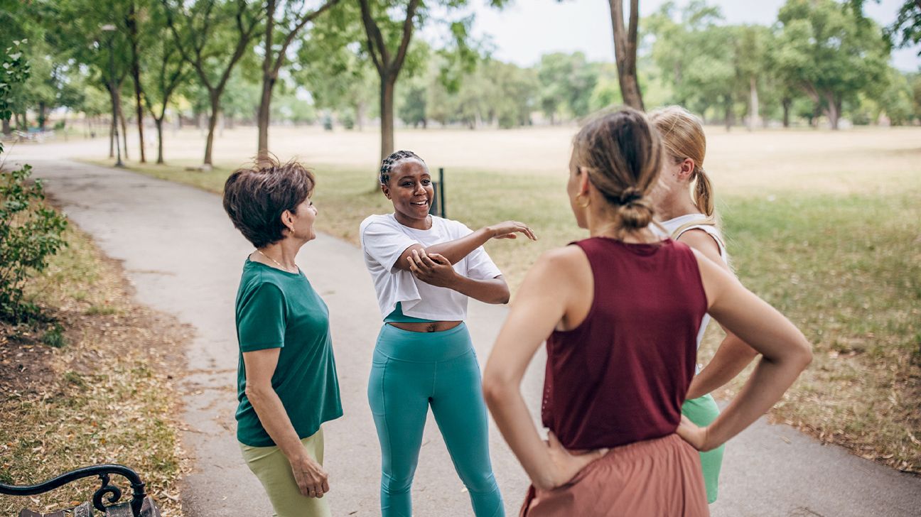 four women exercising together in park