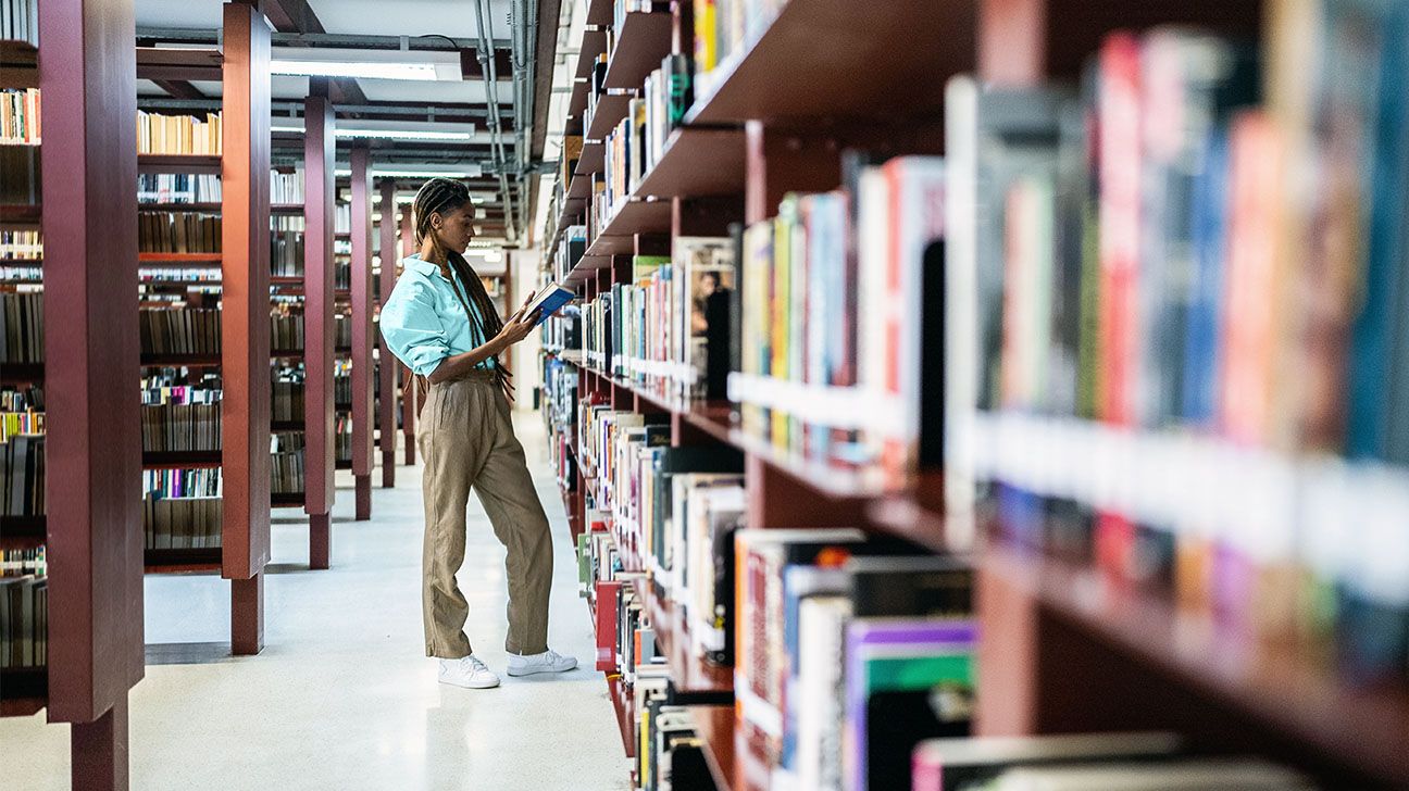 Black woman searching a book shelf