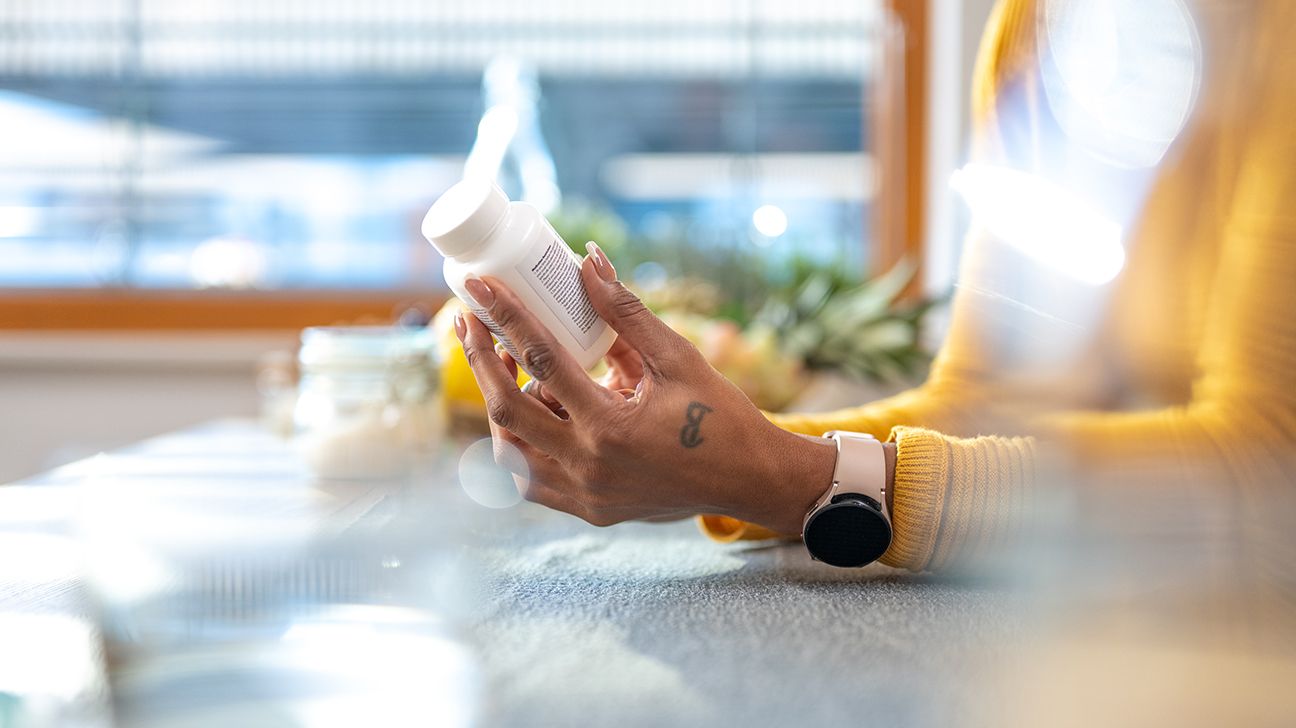 Close-up of woman's hands holding pill bottle to read its label