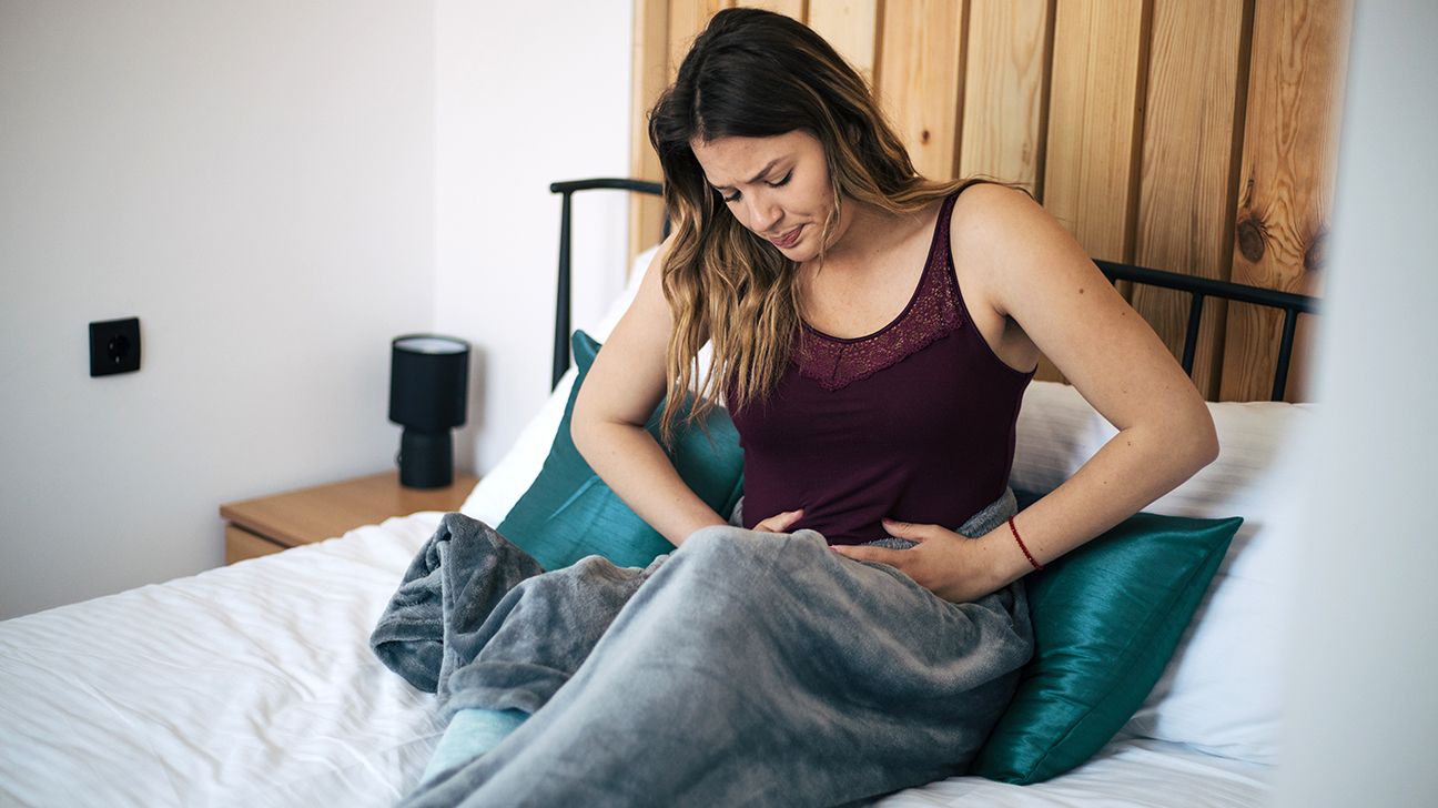 a woman clutching her abdomen in bed
