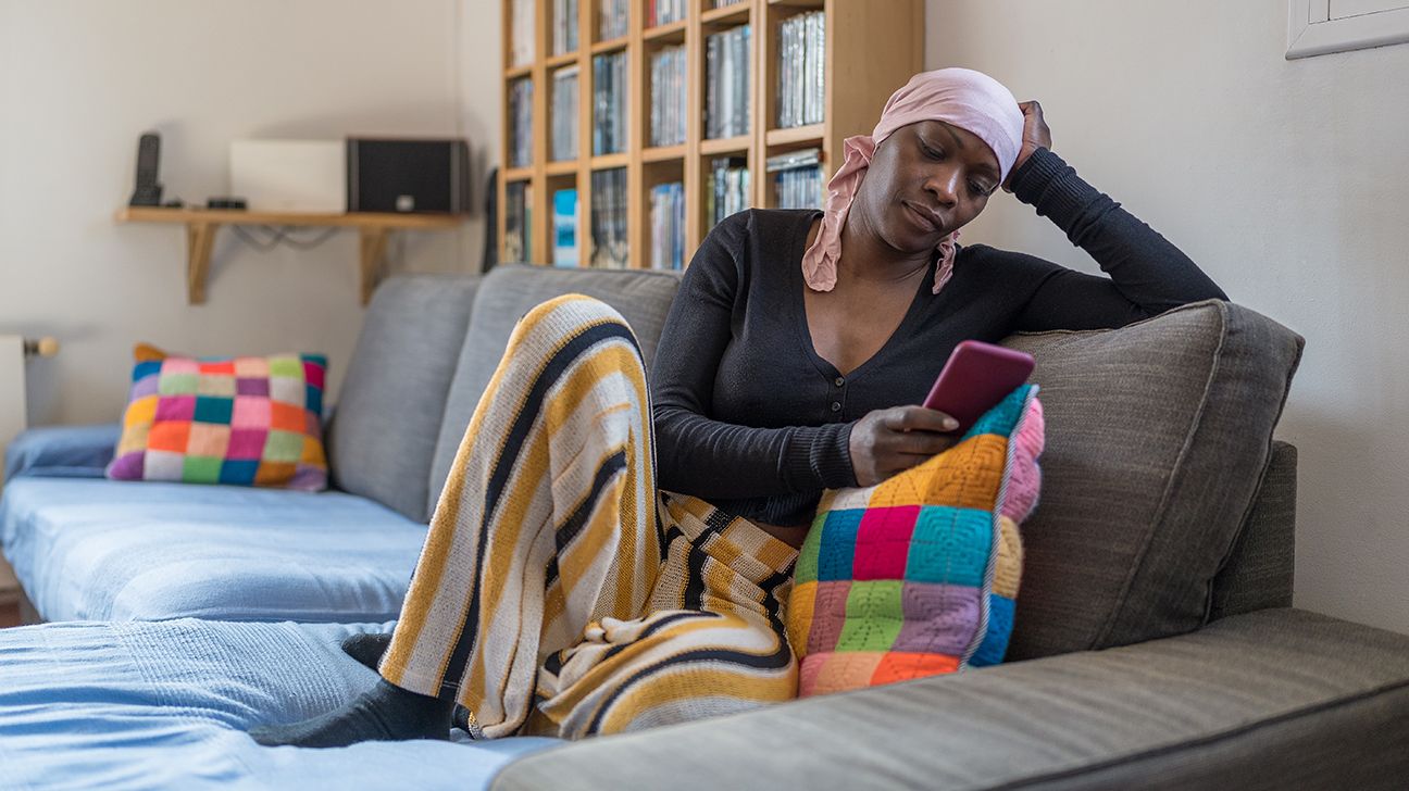 woman wearing head scarf sitting on couch looking at her phone
