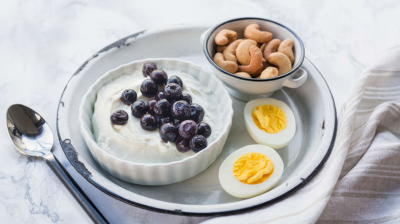 Breakfast bento with yogurt, egg, blueberries, and cashews