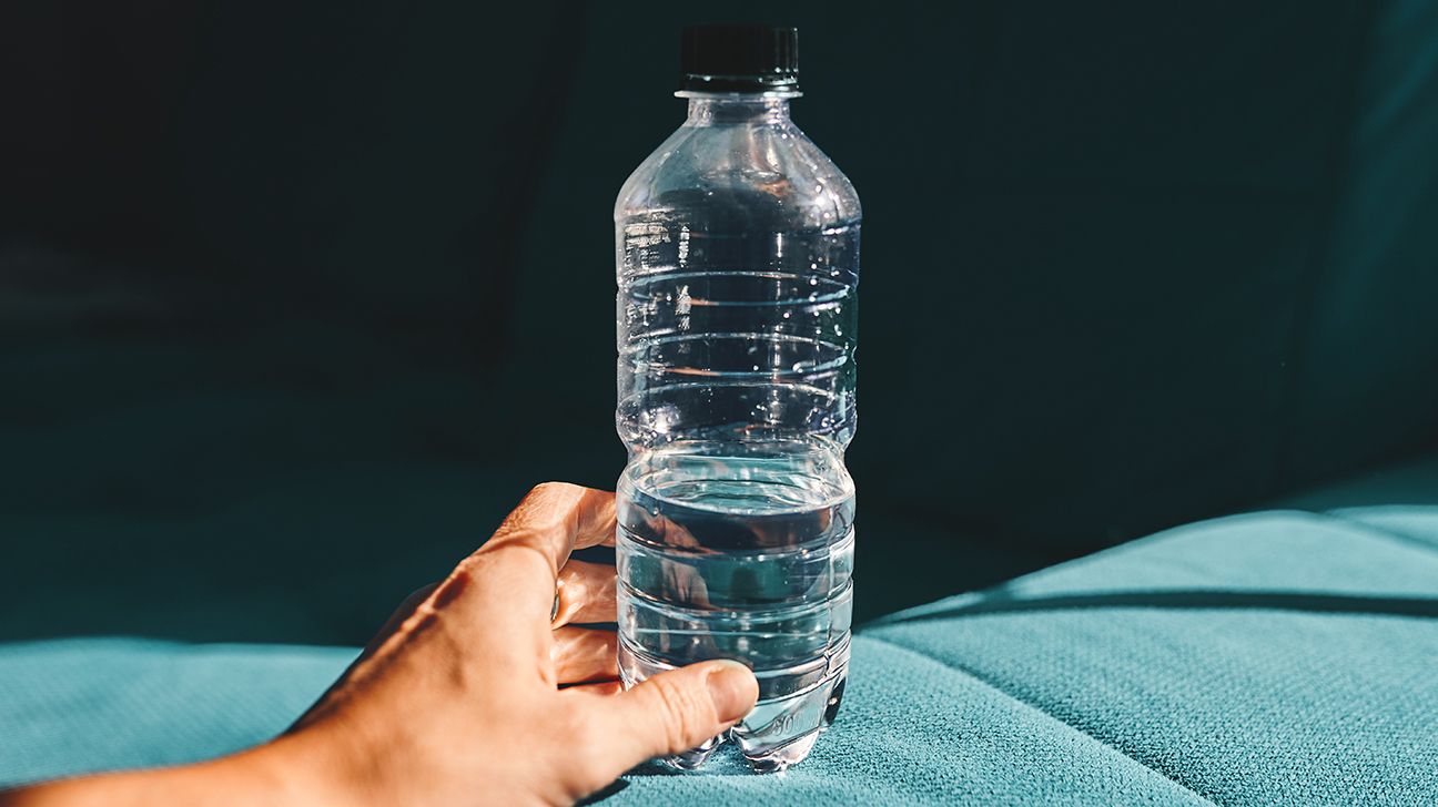 Hand holding plastic water bottle with dark background