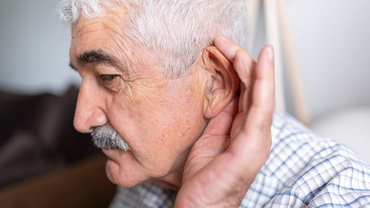senior man holding hand to ear to hear better