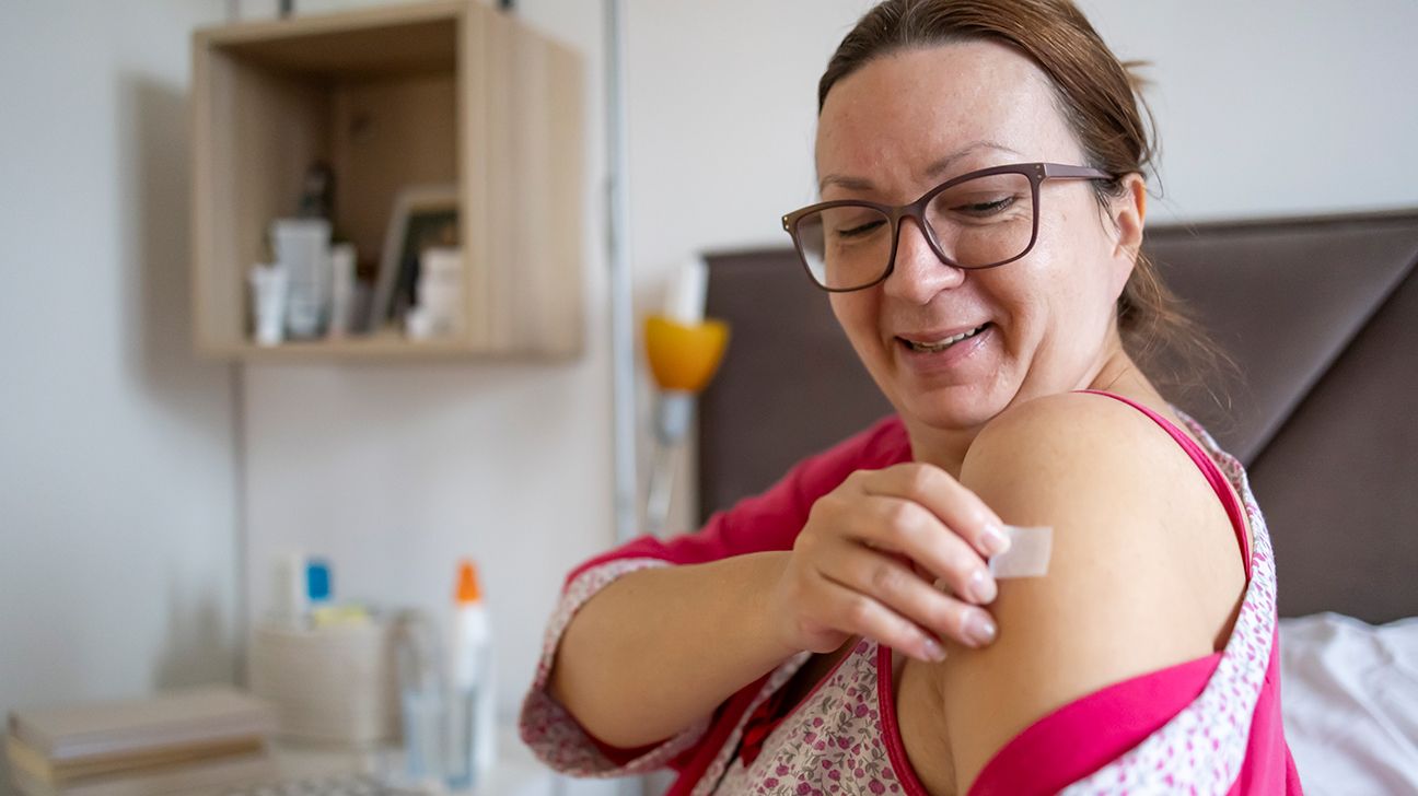 adult female applying menopausal hormone therapy patch to her arm