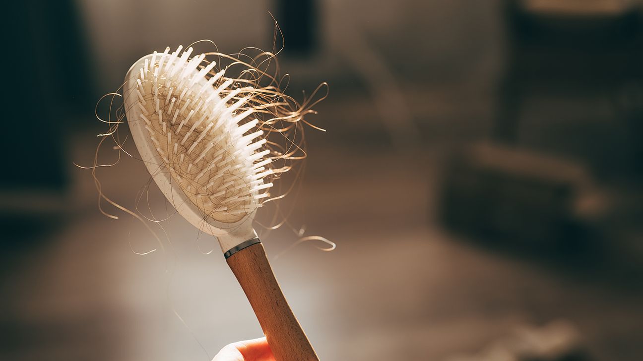 hand holding brush with lots of hair in it