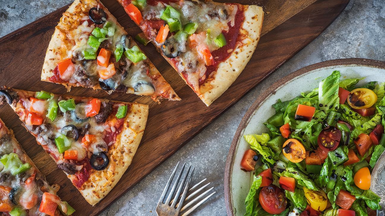 Beef, pepper, and olive pizza with a side salad