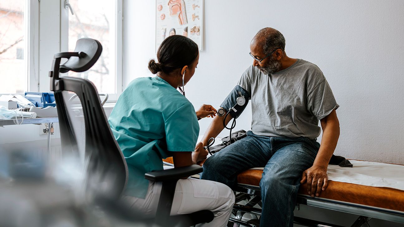 Female doctor checks older male's blood pressure