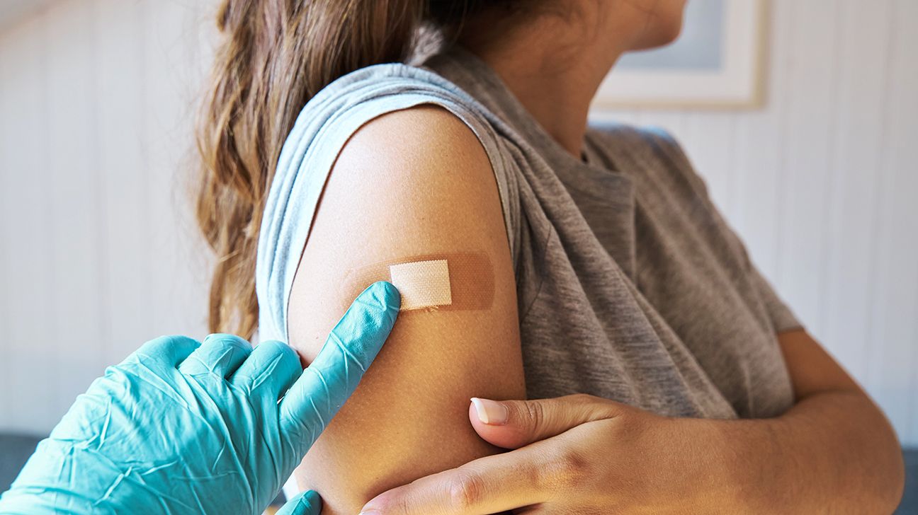 Female receives COVID shot in the arm with bandaid