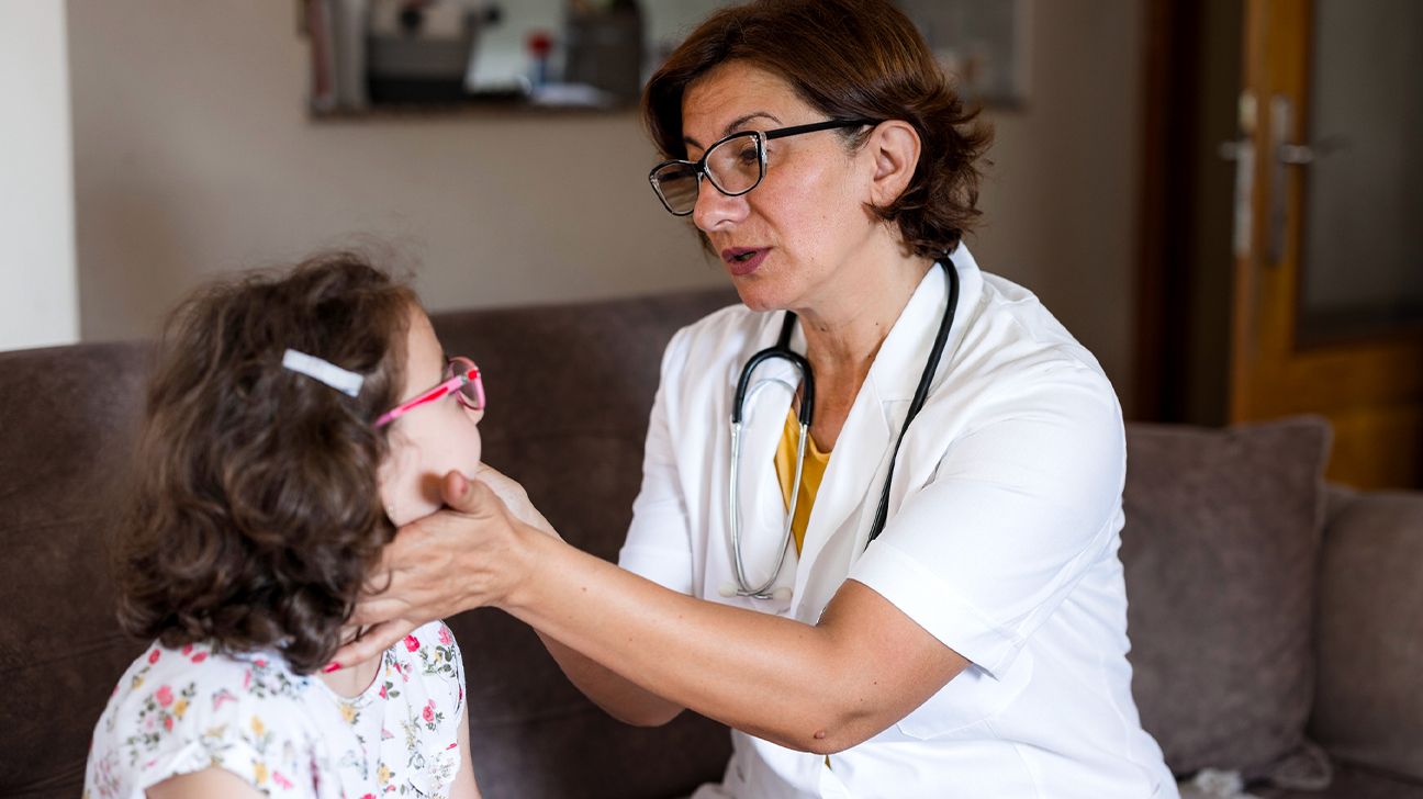 female doctor checking a child's thyroid gland