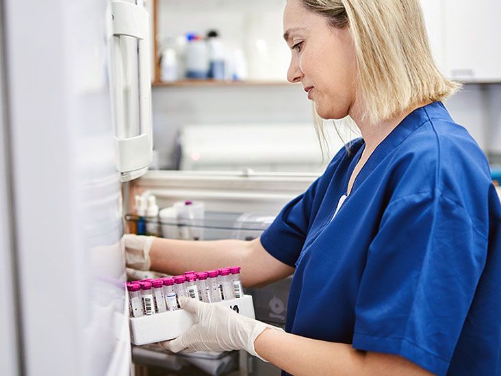 A female healthcare professional is putting medication in the refrigerator.