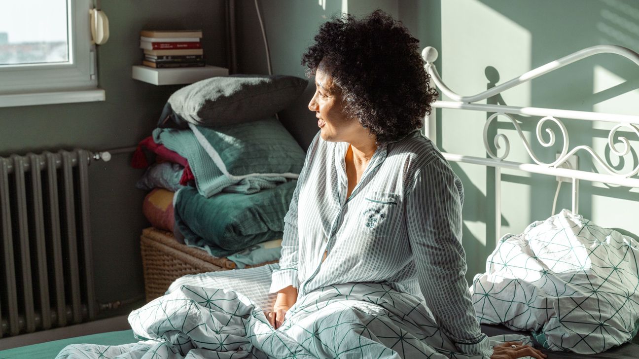 Female in pajamas on bed in morning sunlight