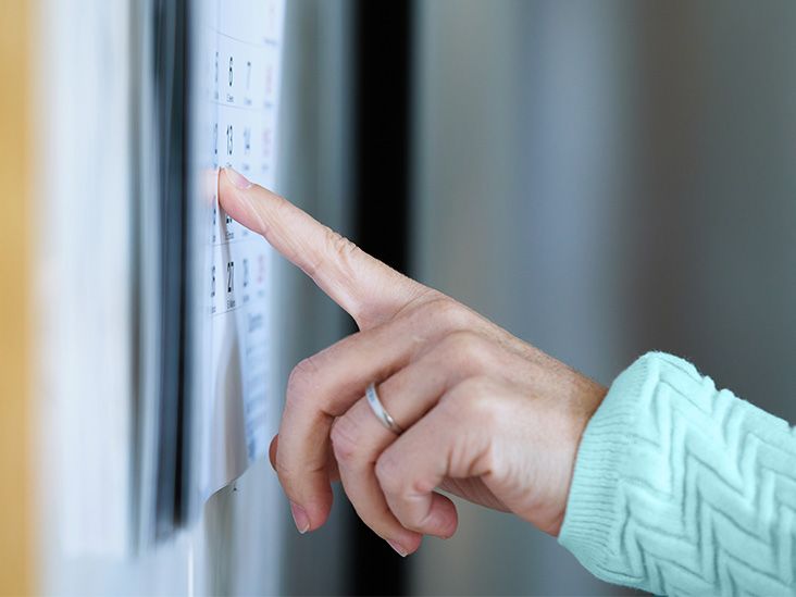 A person used their finger to point at a calendar on a wall.