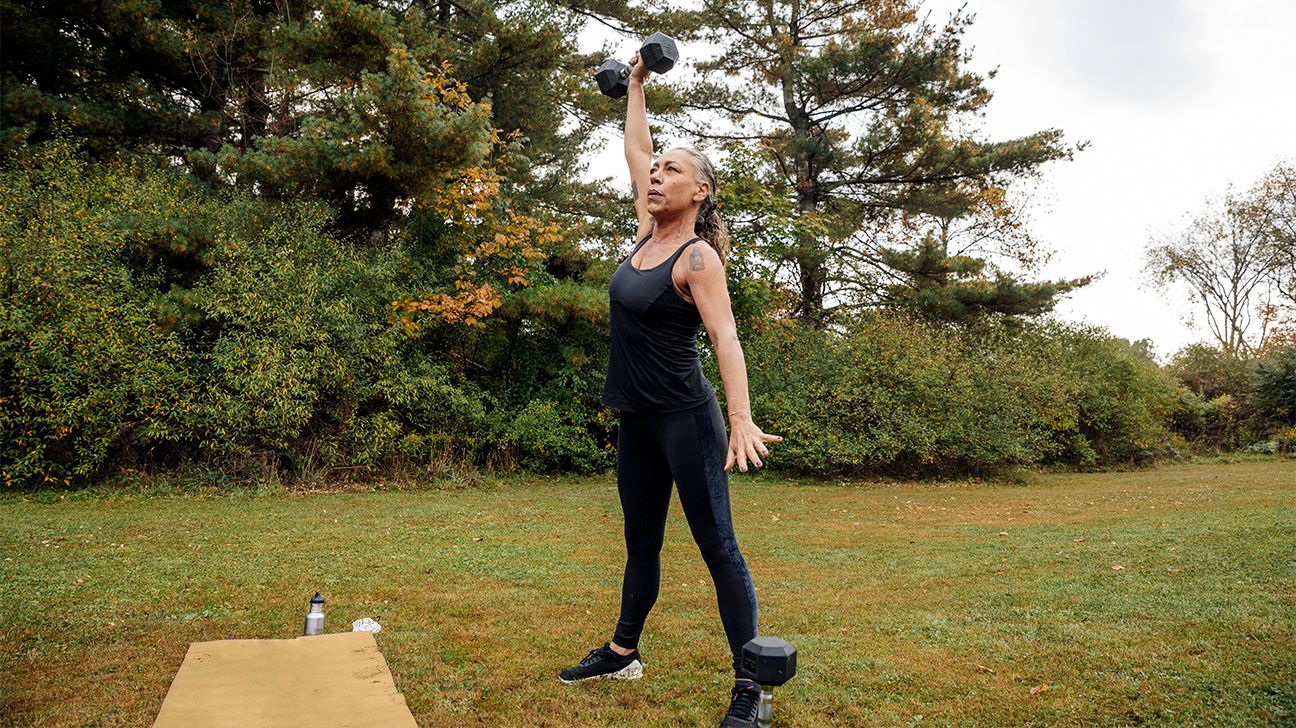 Older female strength training with weights outdoors