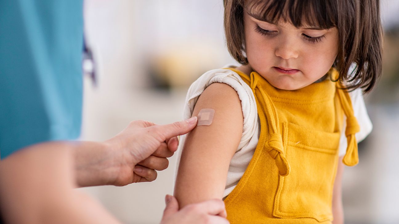 Young child receiving a Band-Aid on their arm after receiving a vaccine