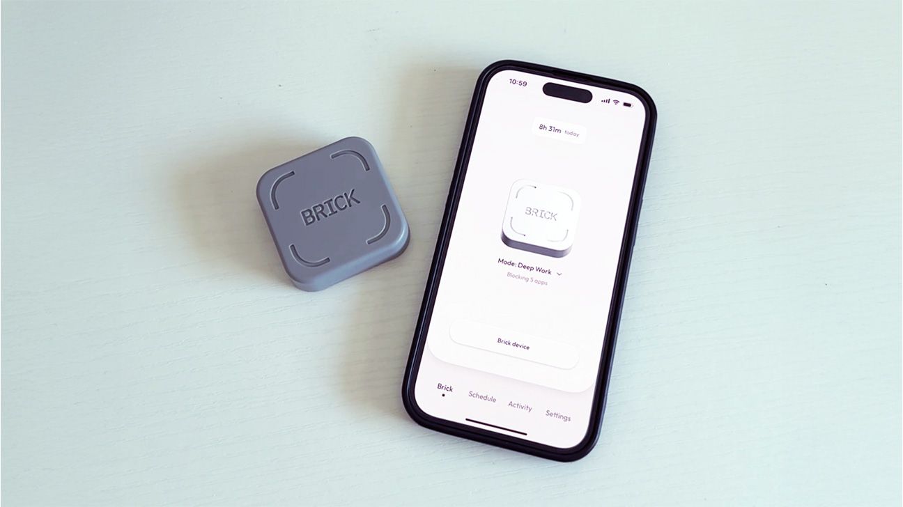 A Brick phone lock device placed beside a smartphone, on a flat surface.