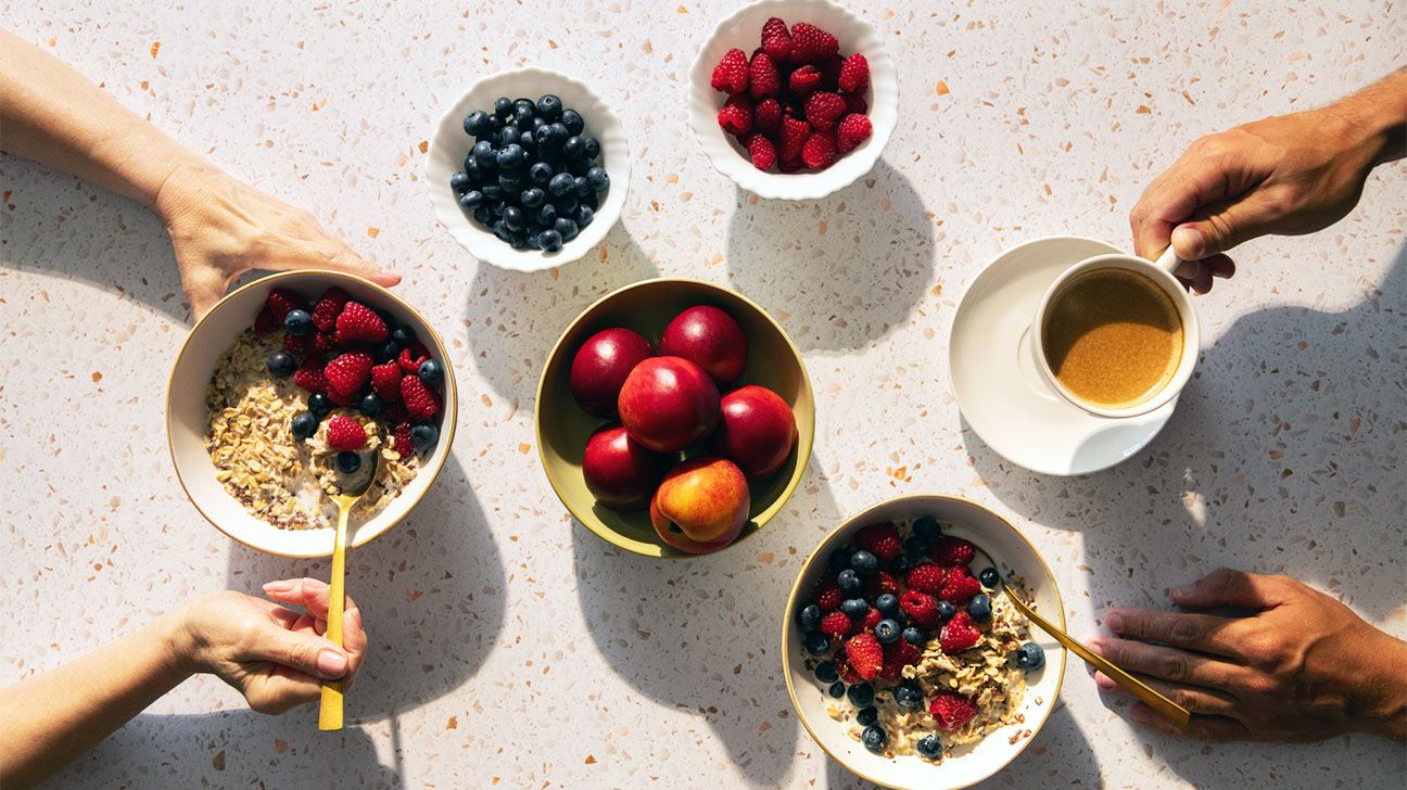 People's hands at a table, eating oatmeal