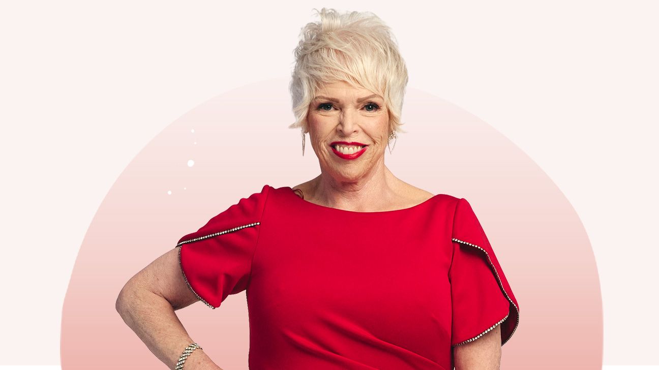 Lori in red dress, smiling with her hands on her hips