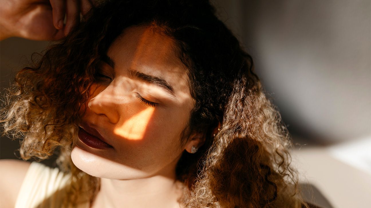 Younger female with her eyes closed as sun streams onto her face