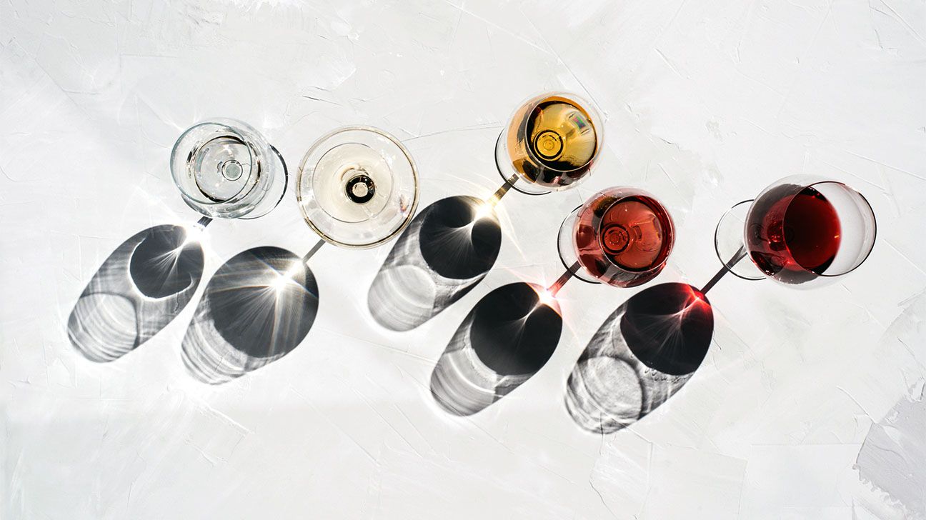 Wine glasses and their reflections against a white background