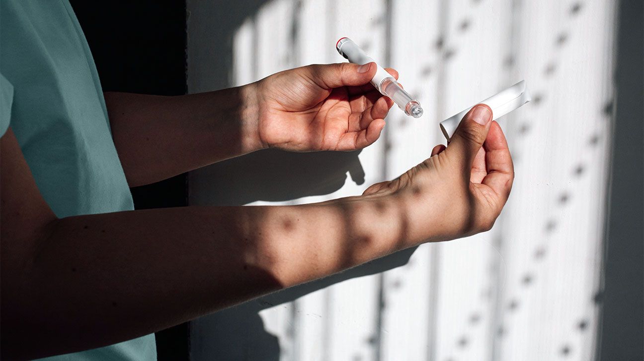 Person holding a GLP-1 pen in shadows