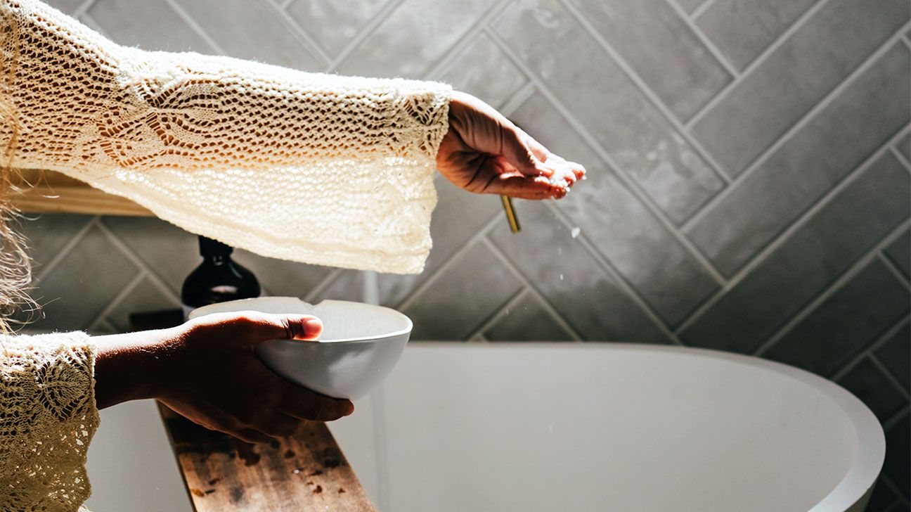Female wearing crochet sweater with bowl in bathroom