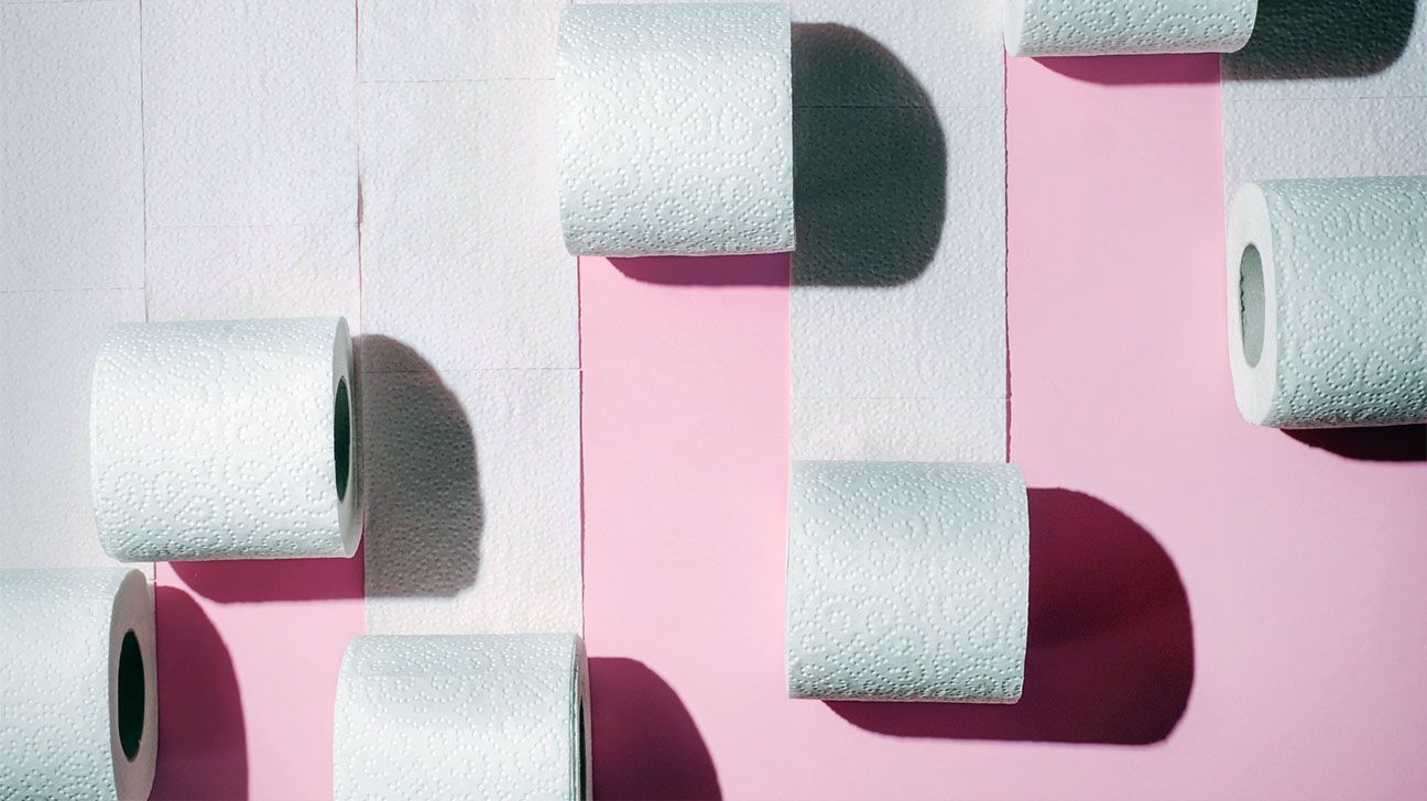 Unrolled rolls of toilet paper against a pink background