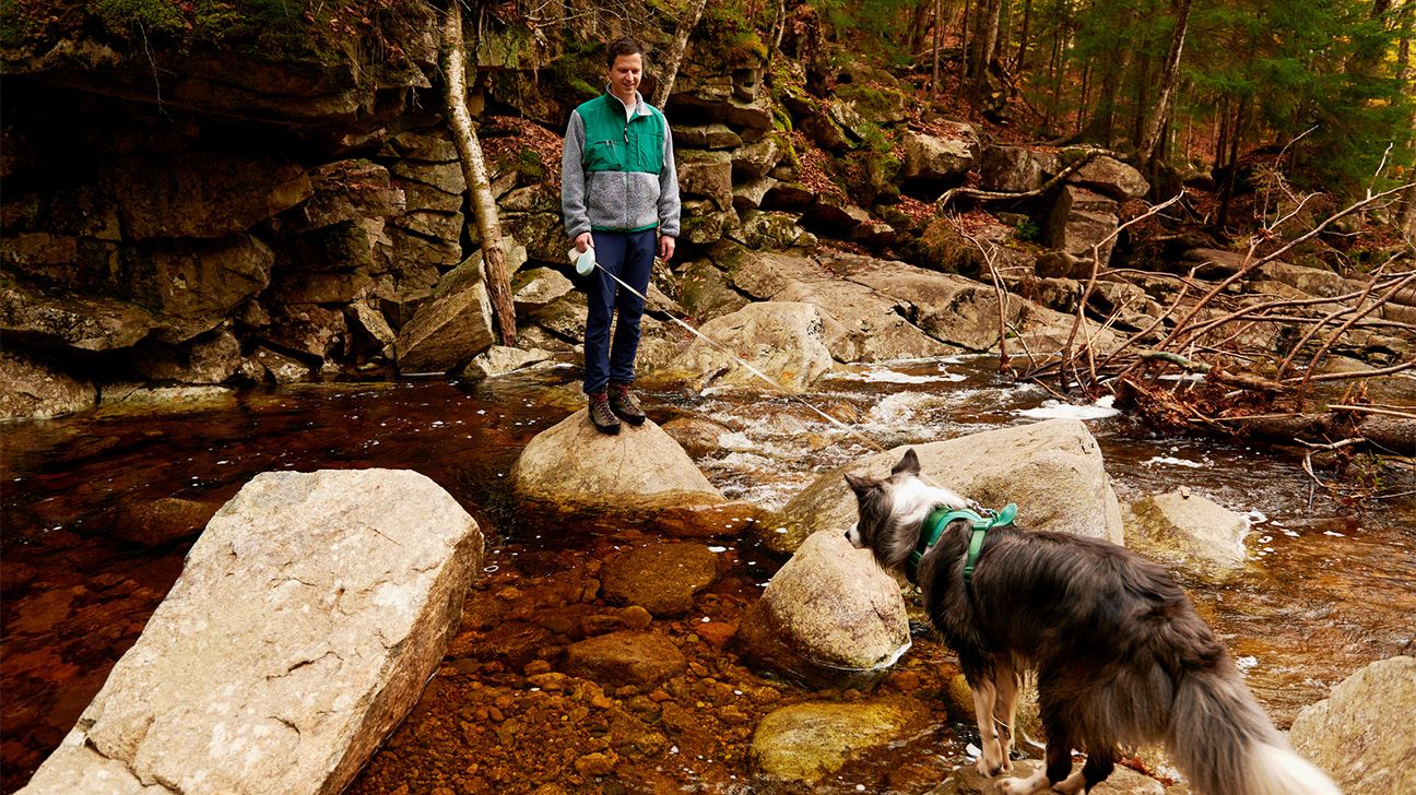 Person hiking near a stream with his dog