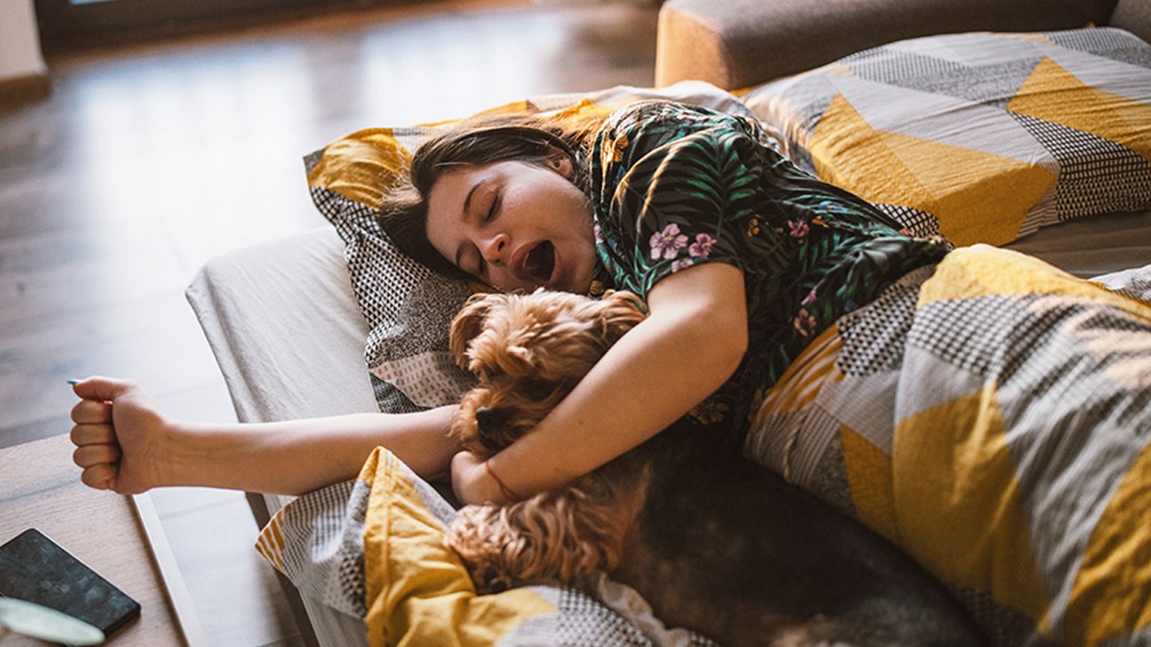 Female falling asleep in bed while cuddling her dog