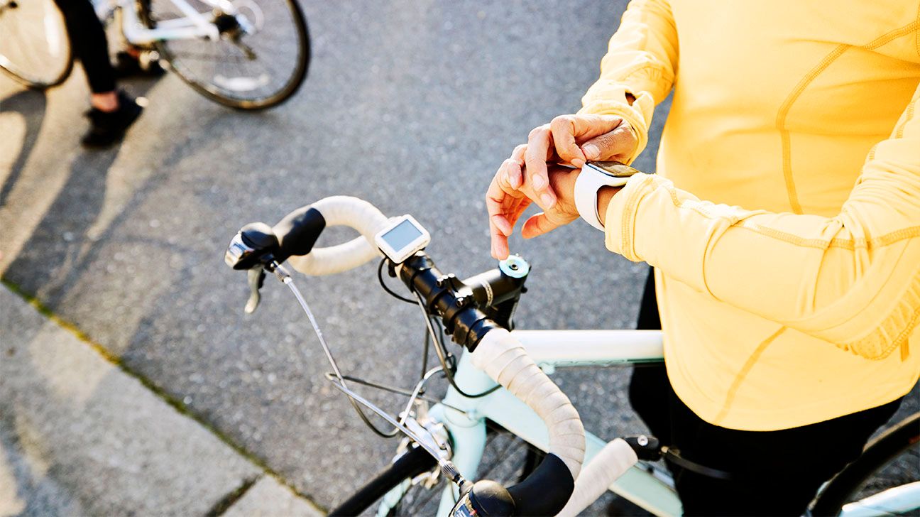 Close up of female in yellow biking gear checking smartwatch