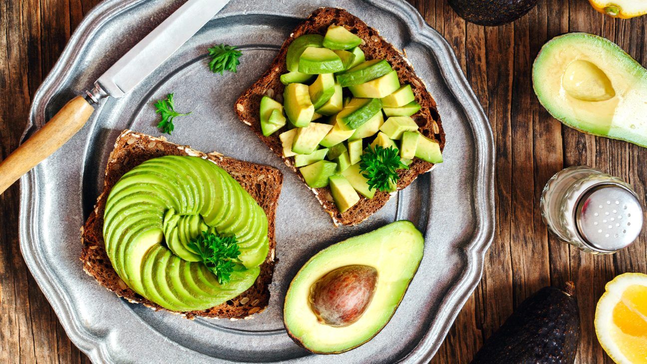 A plate with half an avocado and two slices of avocado on toast