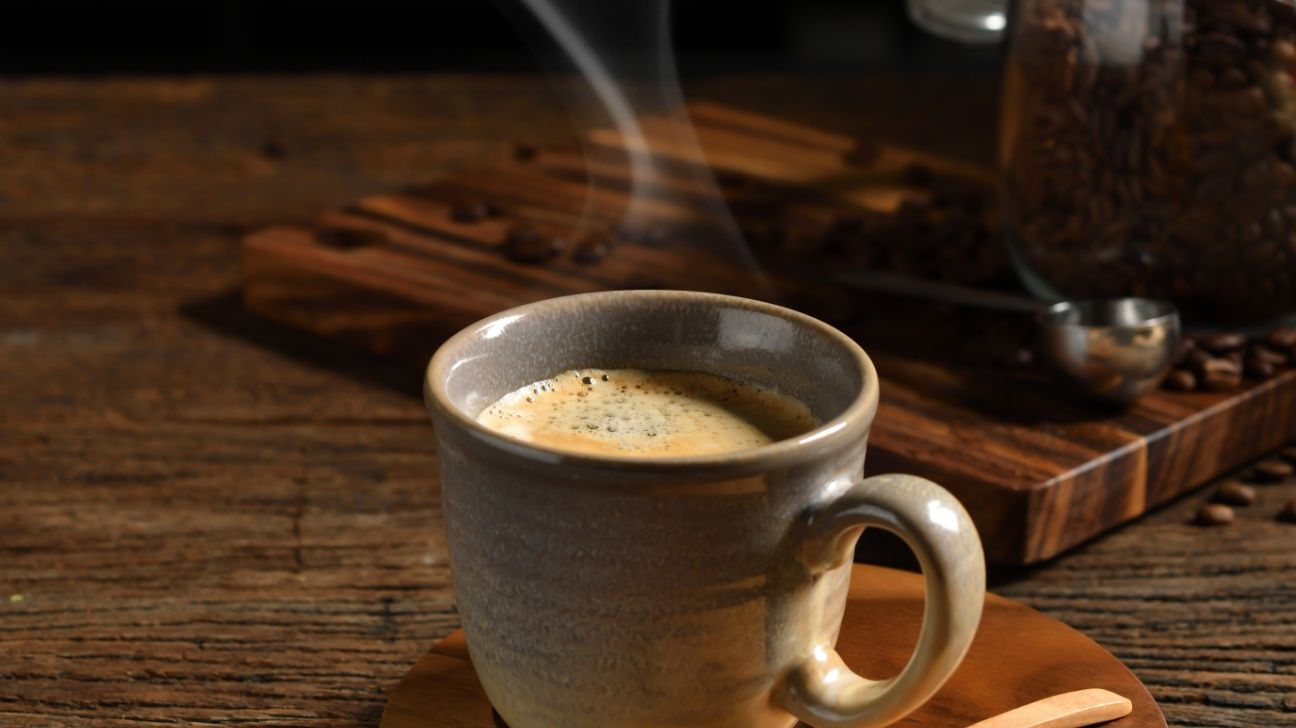 Cup of black coffee against a wooden background
