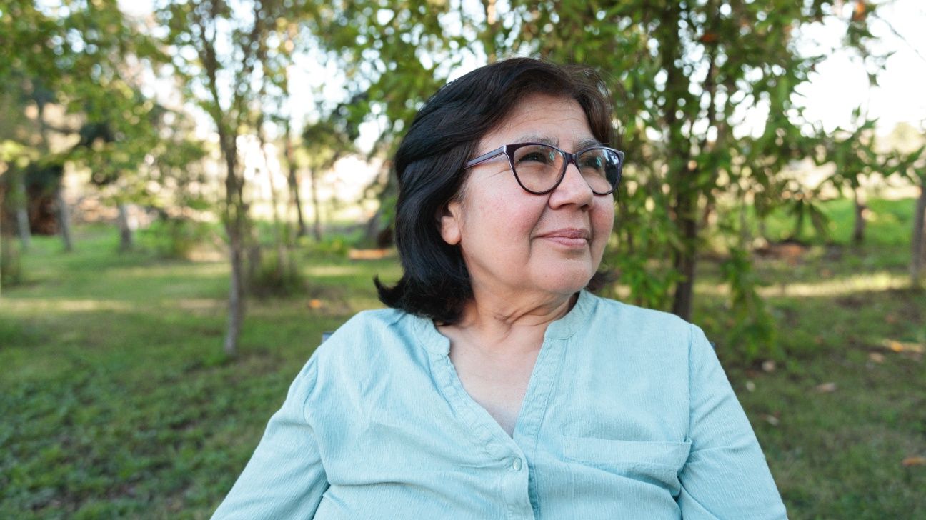 A senior woman wearing glasses outdoors.