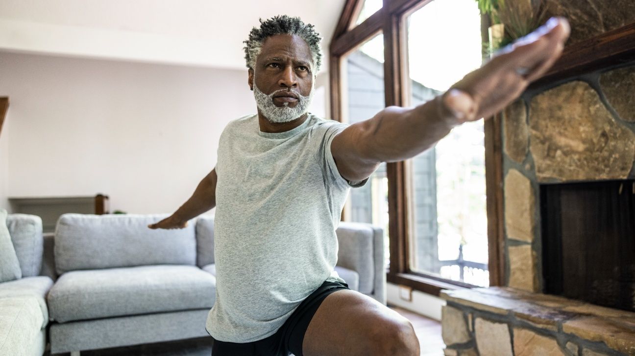 Older male practicing yoga in living room