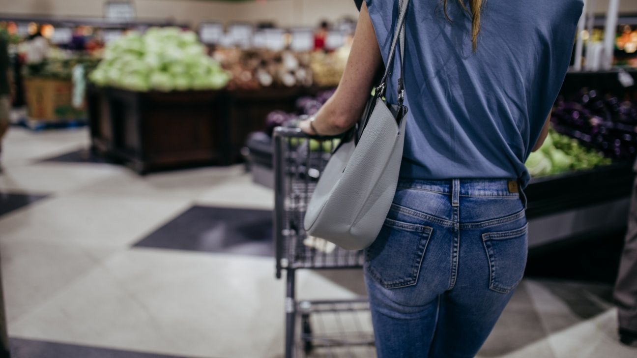 Female pushing a shopping cart in the produce section of a grocery store