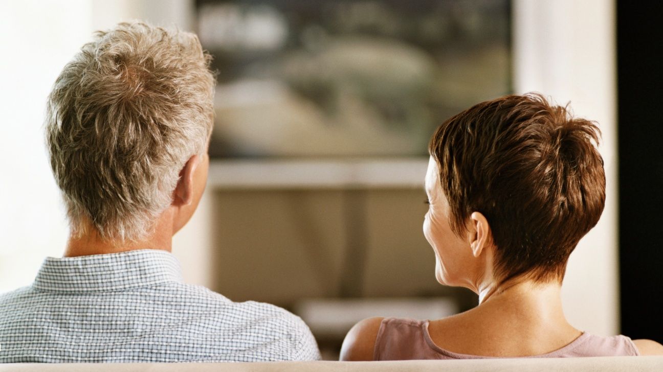 Middle aged couple sitting on a sofa watching TV